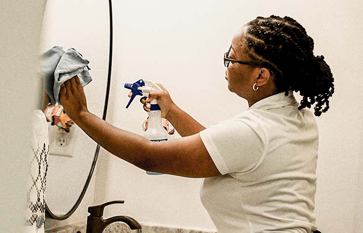 Clean by Nature employee cleaning a mirror